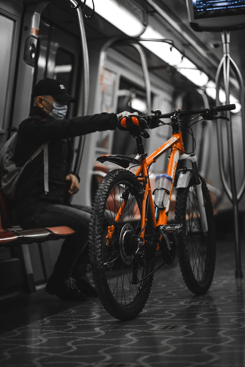 A masked man carries a bicycle on a metro train in İstanbul, Turkey, reflecting urban mobility.